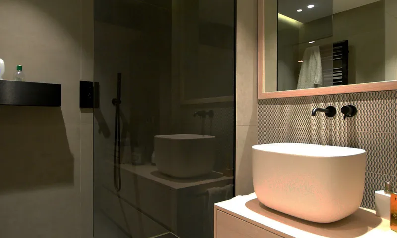 Dark tiled bathroom with a round counter-top basin and large mirror