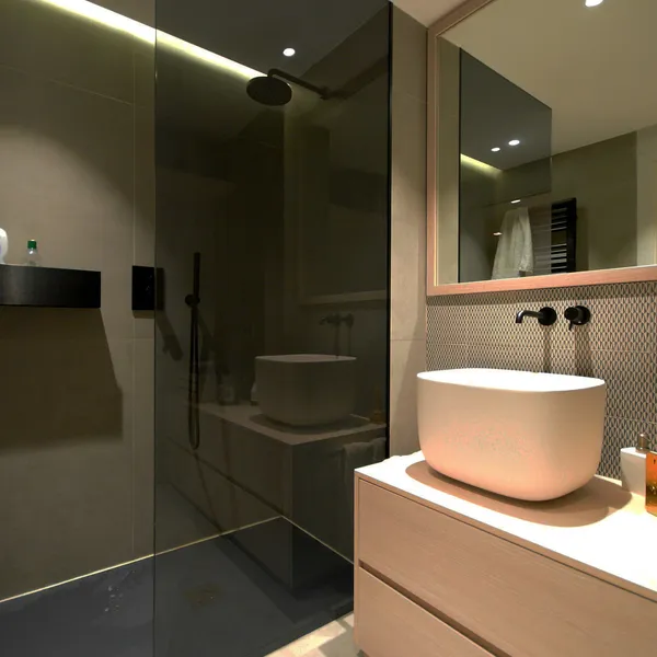 Dark tiled bathroom with a round counter-top basin and large mirror