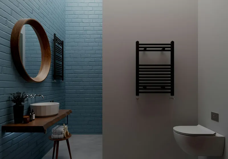 Dark tiled bathroom with a round mirror, wall-hung basin and heated towel rail