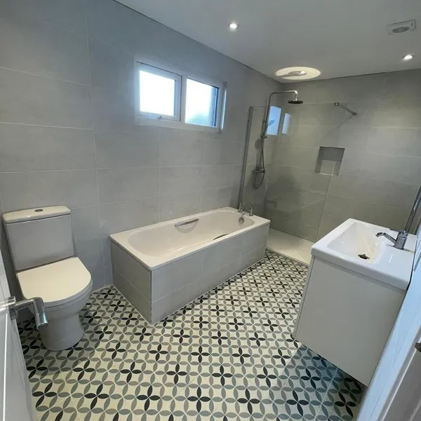 Bathroom with a bath, a walk-in shower with a recessed niche, grey wall tile and a patterned floor