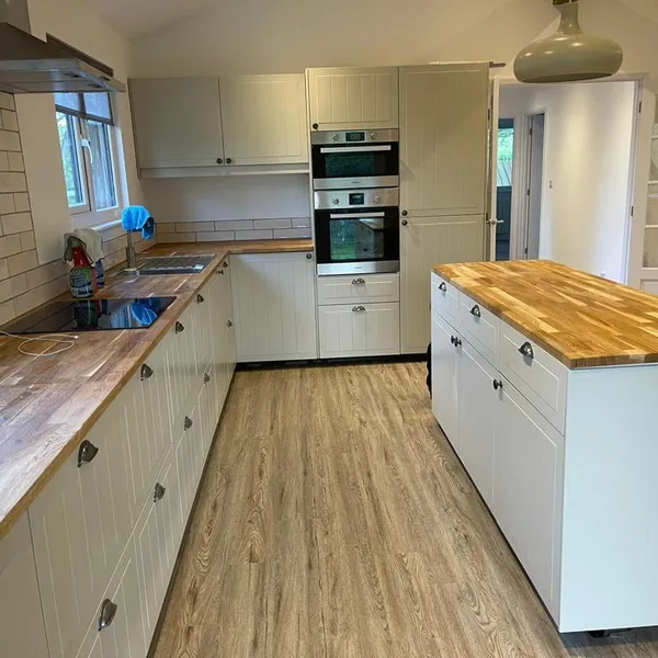 Kitchen with cream shaker-style units, oak worktops and an island with an oak top, and wood-effect flooring