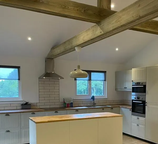 Open-plan kitchen and living space under a vaulted ceiling with exposed timber beams