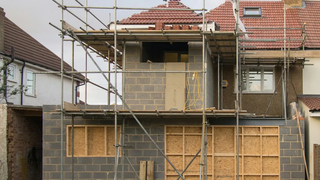 House extension under construction, wrapped in scaffolding