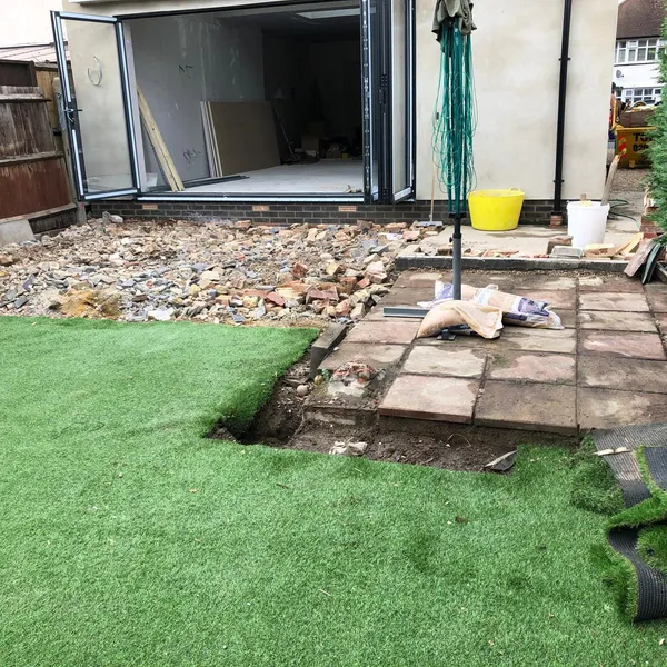 The extension shell with its bifold doors open, while the old slab patio is lifted in front of it