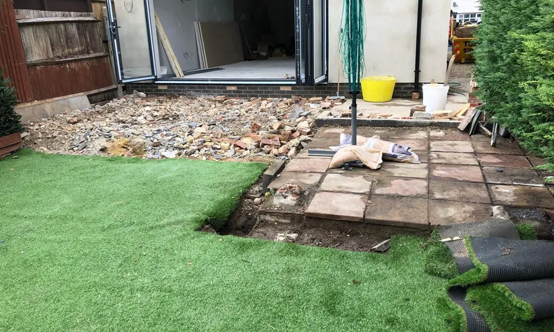 A single-storey rear extension mid-build, with the bifold doors in and the old patio being lifted in front of it