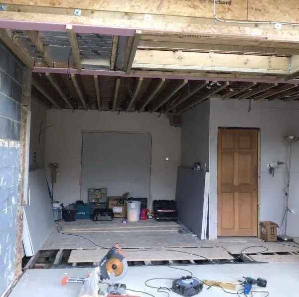 Inside the extension during the build, with the roof joists and rooflight openings exposed and the floor still in progress
