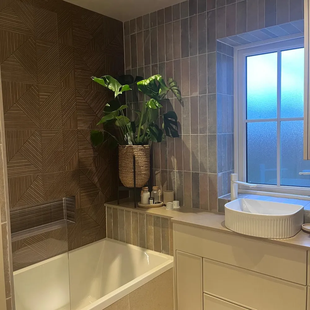 Family bathroom with a bath behind a glass screen, a fluted basin on a cream vanity unit and textured brown wall tile