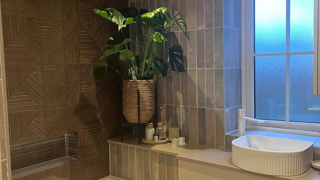 Family bathroom we refitted in Sussex, with a bath behind a glass screen, a fluted basin on a vanity unit and textured wall tile