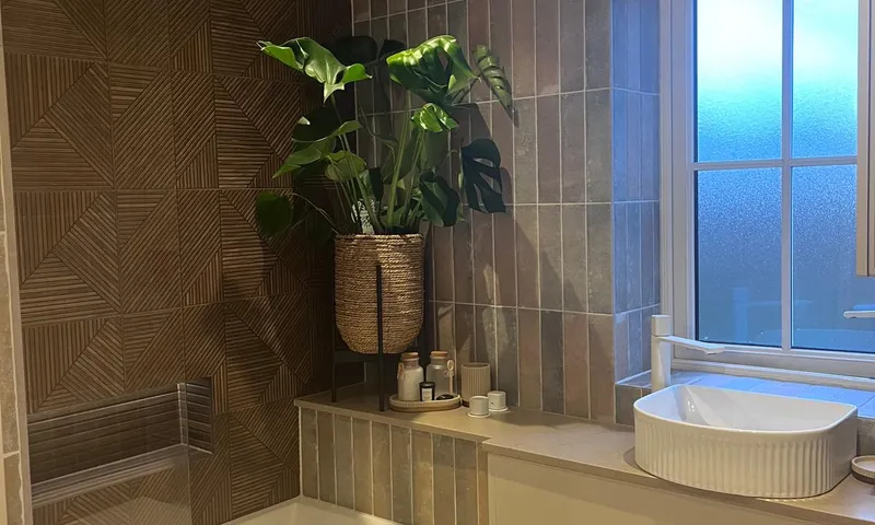 Family bathroom we refitted in Sussex, with a bath behind a glass screen, a fluted basin on a vanity unit and textured wall tile