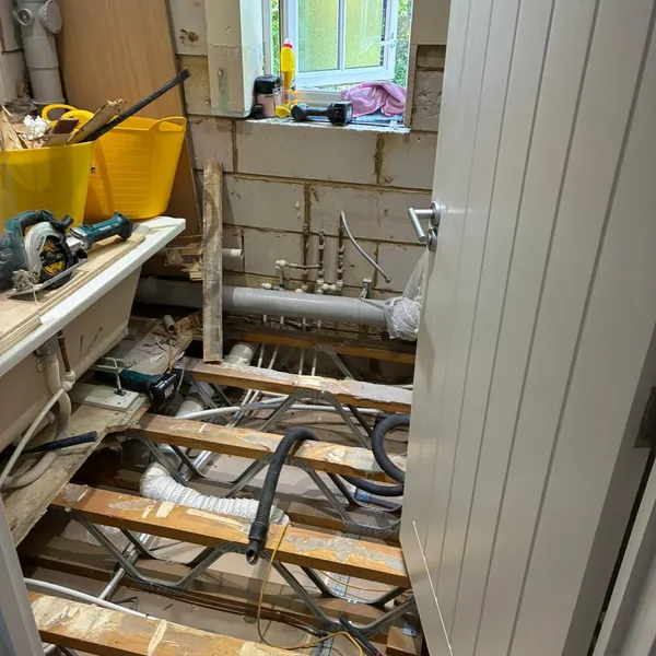 Bathroom floor lifted to the joists, with the pipework exposed during the strip-out