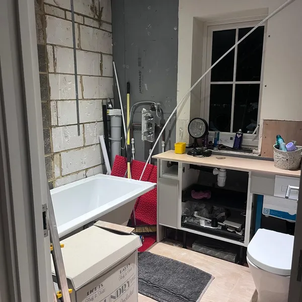 The same bathroom during the strip-out, with the old tiles off the walls and the bath and WC still in place