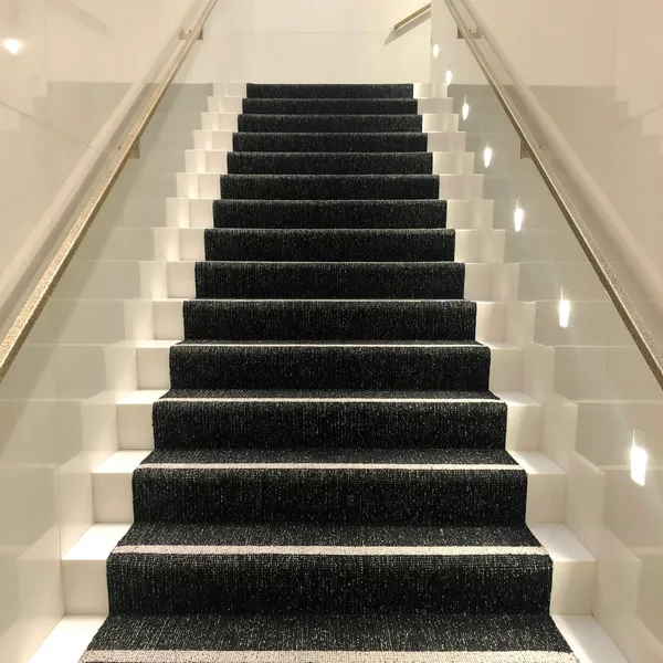Staircase with a dark carpet runner and white painted risers