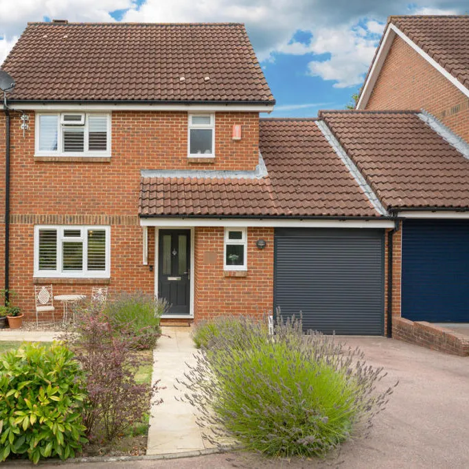 Front of a red brick house in Horsham, with the original roller garage door kept on the converted garage beside the front door