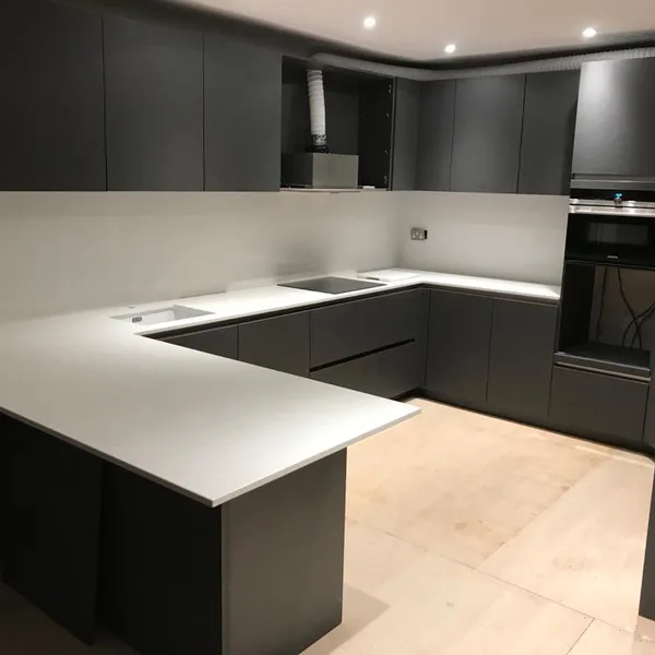 Bespoke charcoal handleless kitchen with a white worktop and breakfast bar, in the final stages of fitting