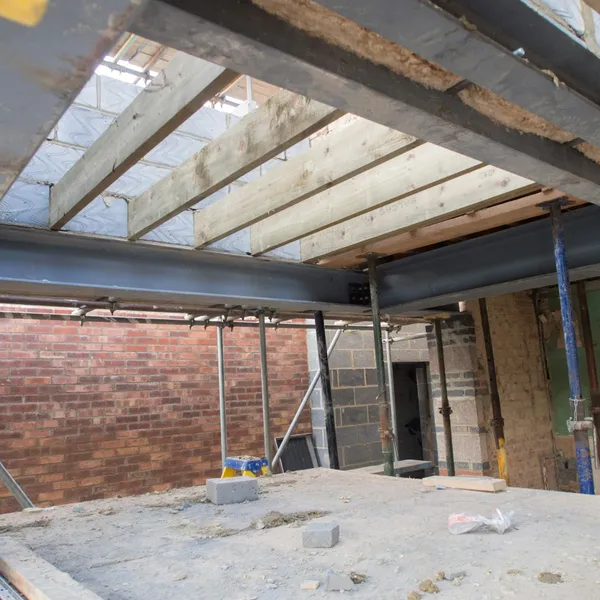 Interior of a property mid-renovation, with exposed brickwork and new timber roof joists